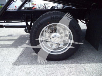 Wheel and tire of a truck chassis showing a polished steel rim and black tire with sidewall text.