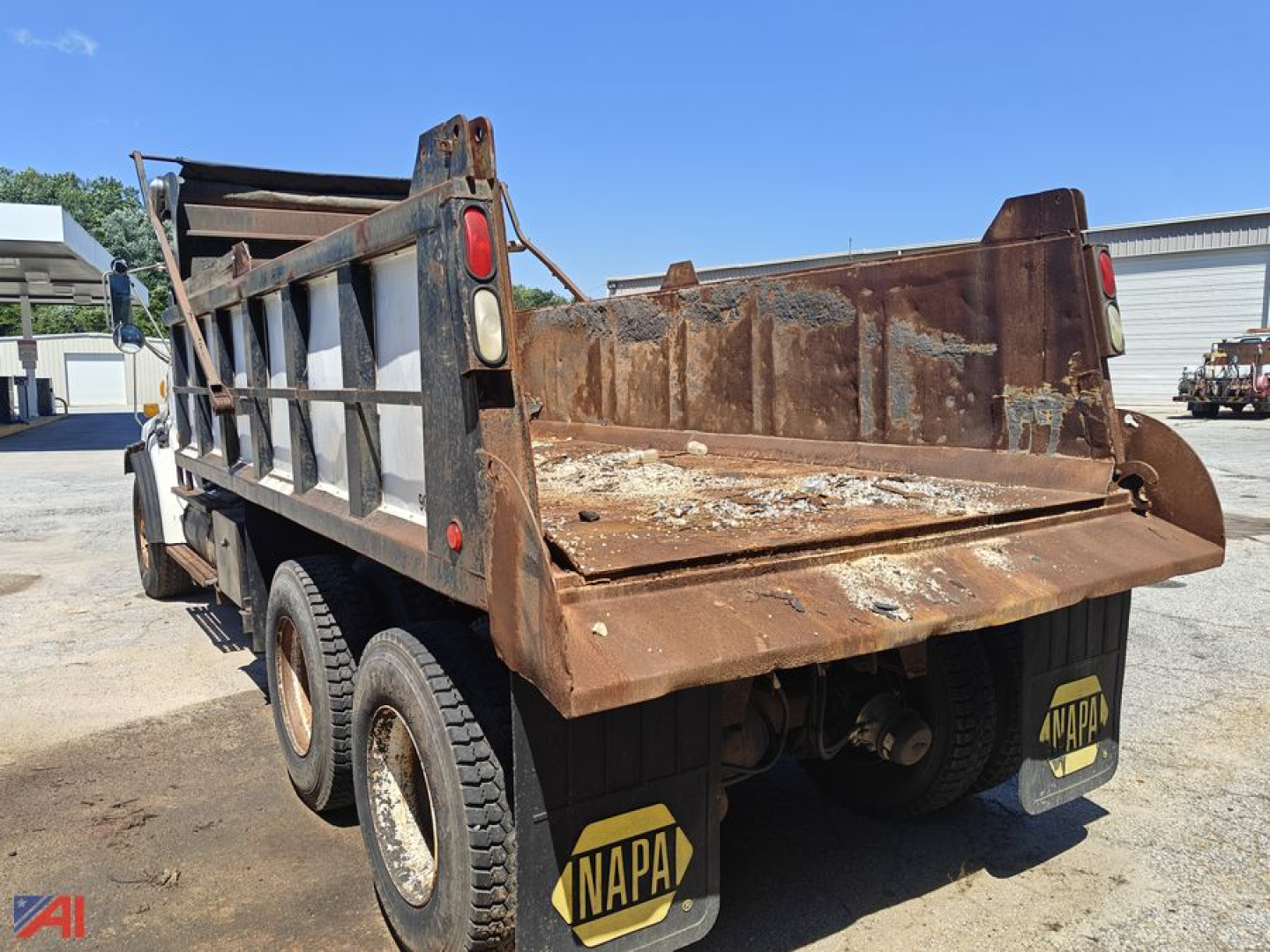 Dump truck showing rusted bed and dual rear axles with mud flaps and NAPA logos.