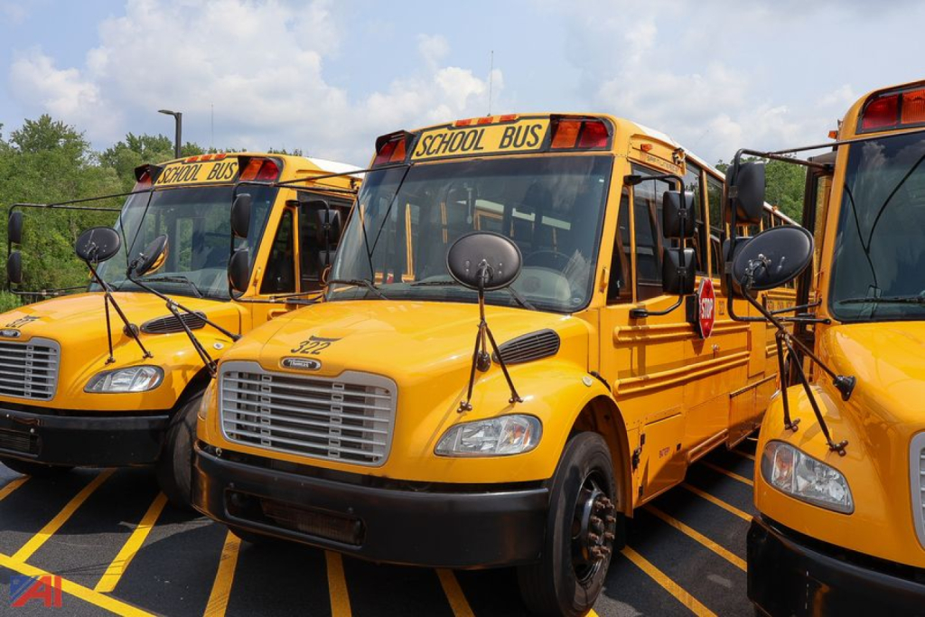 Freightliner Thomas Saf-T-Liner school buses in a parking lot, yellow, front view of central bus with 'SCHOOL BUS' sign on top.