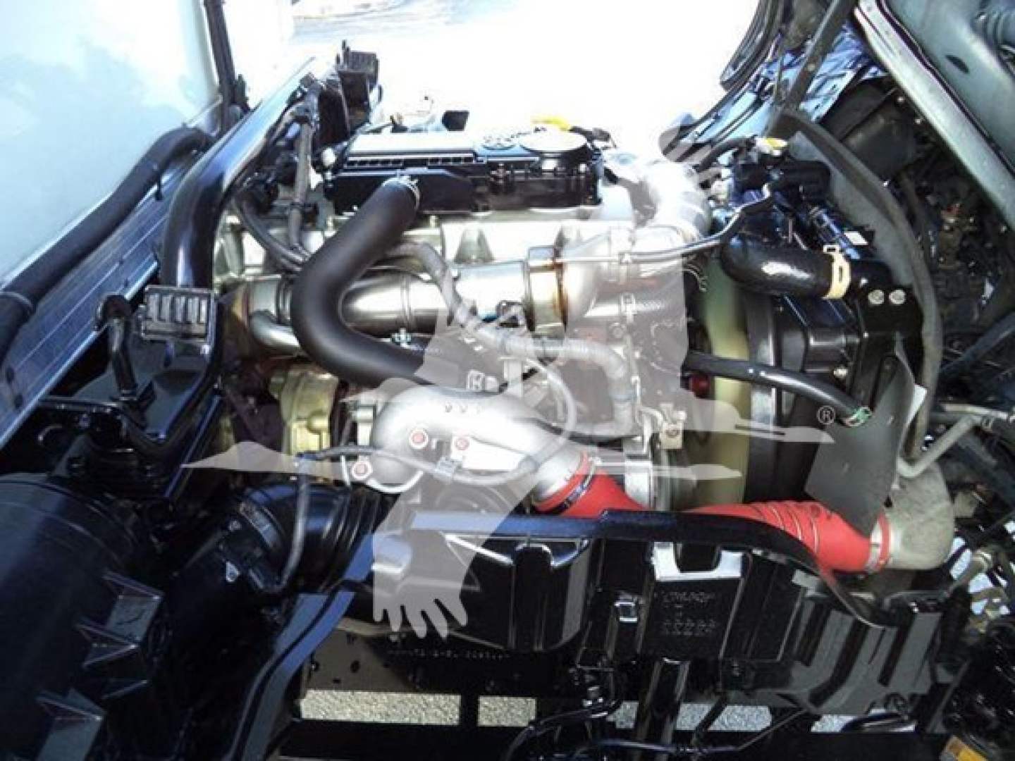 Engine bay of a 2020 Hino 195 refrigerated truck showing turbocharger and intake pipes.
