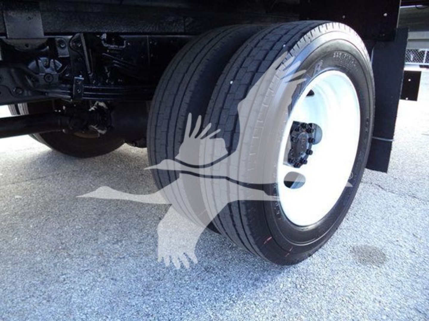 Truck rear wheel and suspension of a 2020 Hino 195 refrigerated truck showing dual rear axle with white steel rim and black tire sidewall.