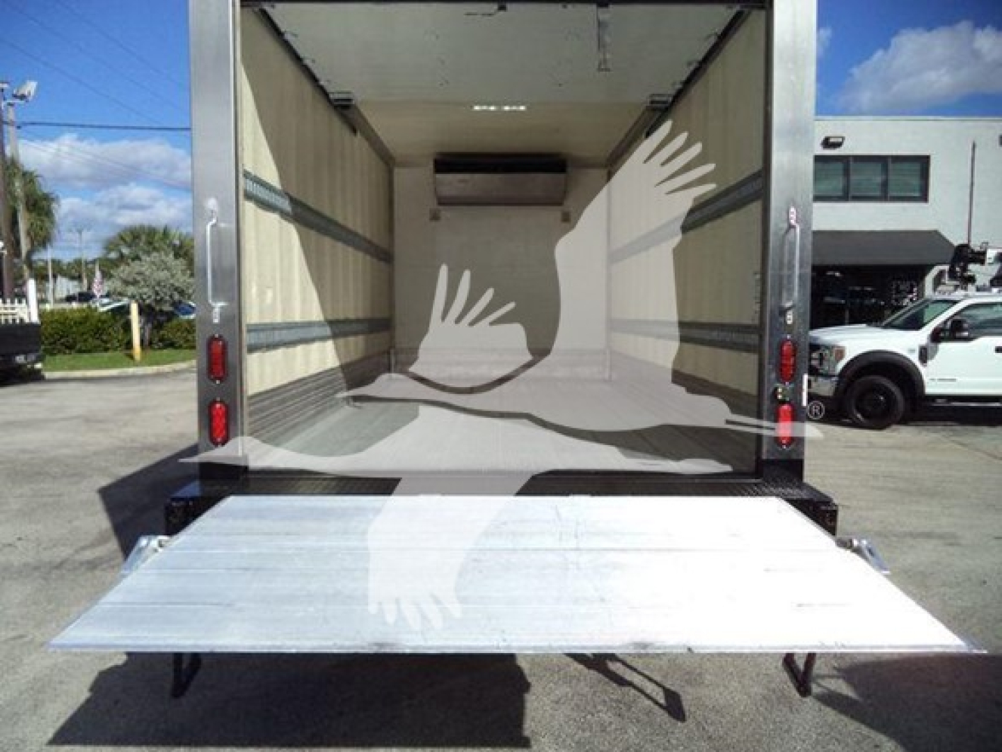 Truck cargo area of a 2020 Hino 195 with rear liftgate extended open, refrigerated box interior visible.