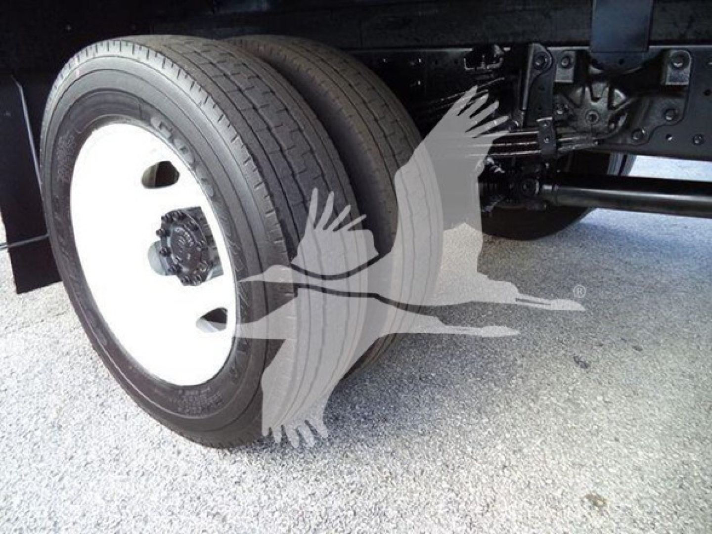 Front wheel and undercarriage of a refrigerated truck showing left front tire and suspension components.