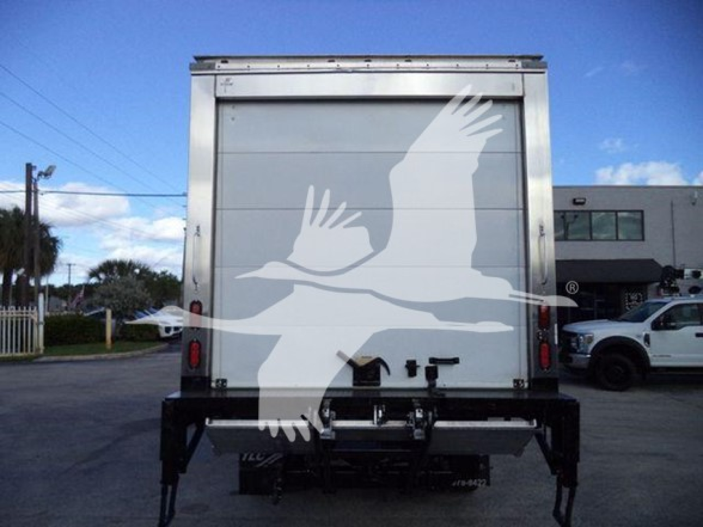 Truck rear view showing refrigerated box and bumper with hitch and latches.