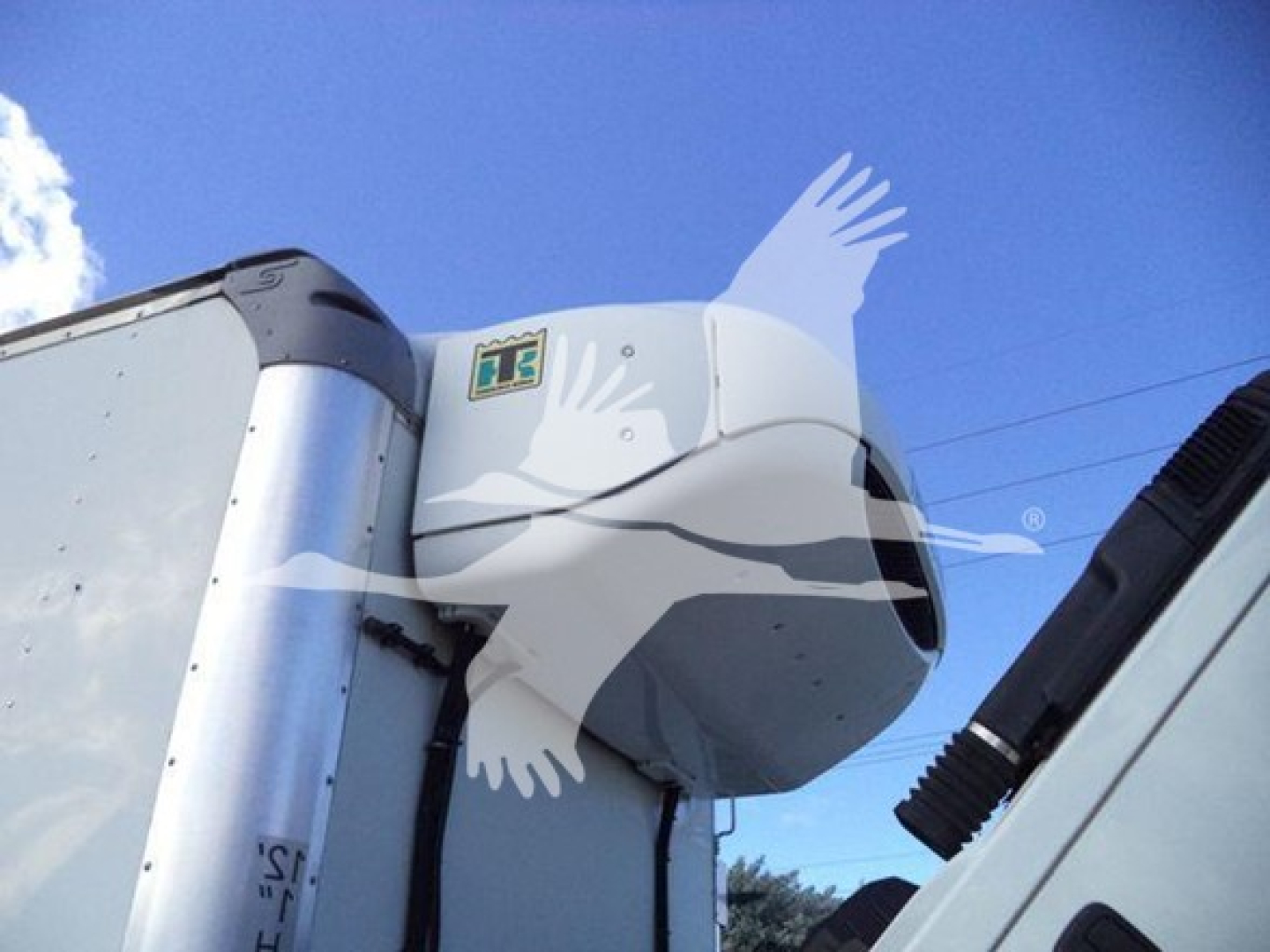 Truck refrigeration unit on a 2020 Hino 195 commercial truck, side view of cab roof with cooling unit housing and blue sky.