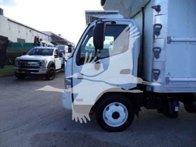 Truck cab of a 2020 Hino 195 refrigerated truck showing front wheel and cargo area; windshield, side mirror, and part of the refrigeration unit visible.