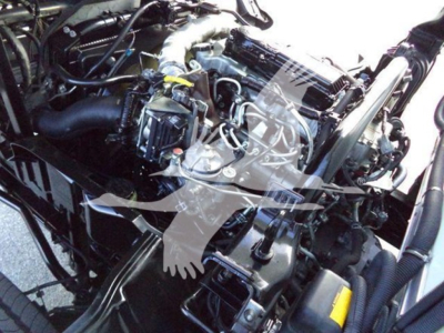 Truck engine bay showing Hino 195 engine components and various hoses, wiring, and a radiator area.