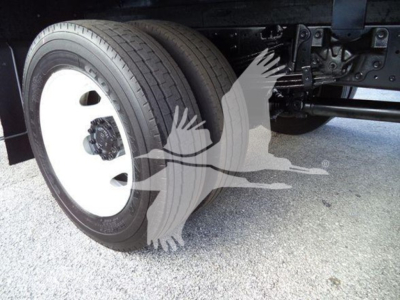 Front wheel and undercarriage of a refrigerated truck showing left front tire and suspension components.