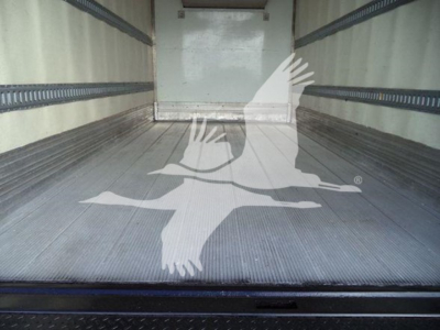 Truck trailer interior showing aluminum ribbed floor and rear door threshold.