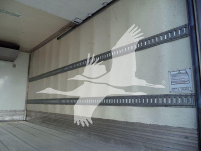Truck trailer interior with metal rails and a watermark of a flying bird/logo overlaying the wall.