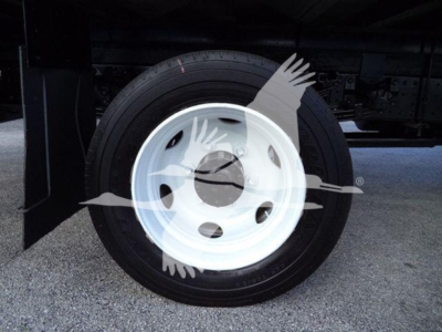 Truck wheel showing white steel rim and black tire under refrigerated truck chassis