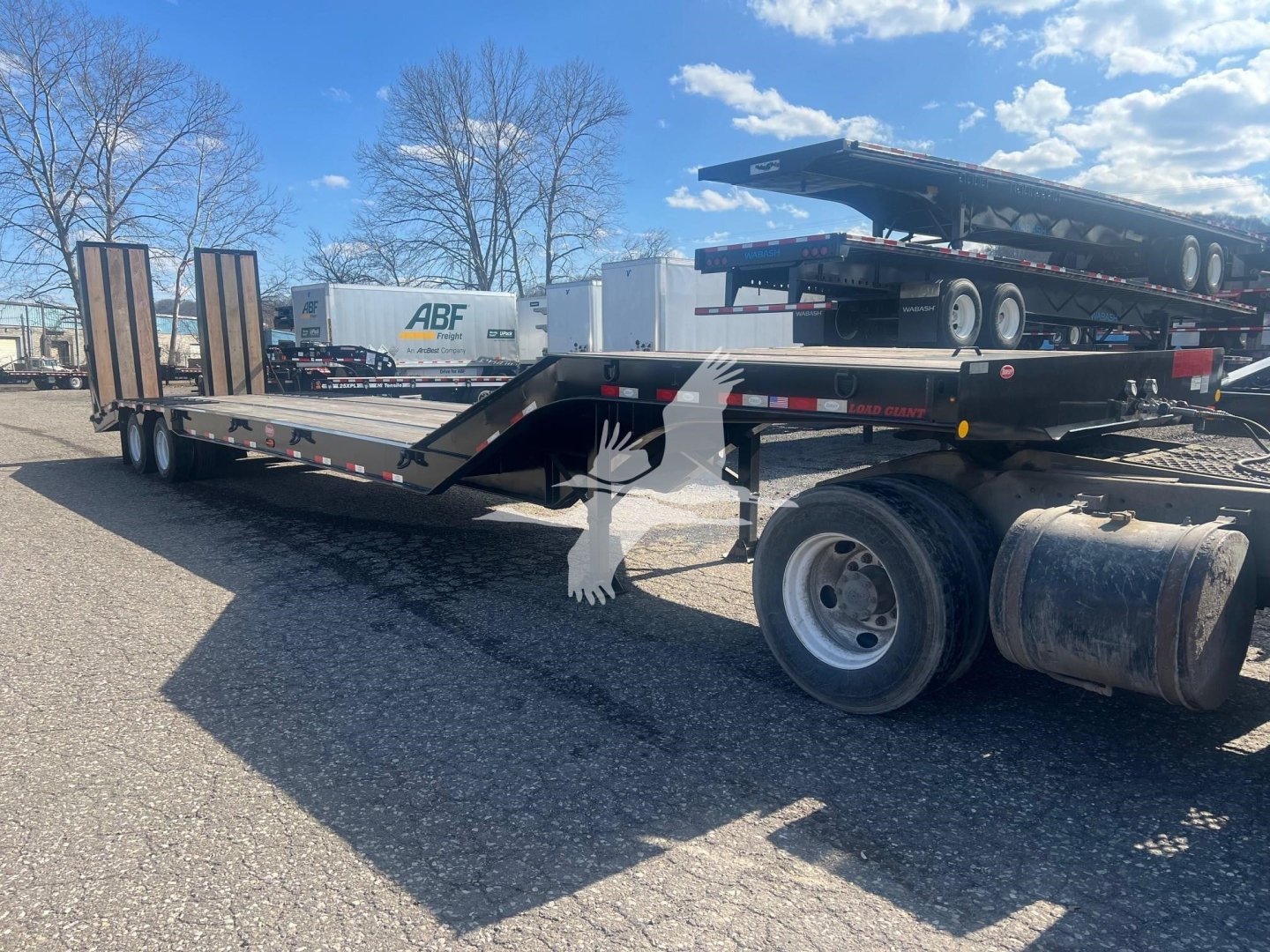 Trailer deck with gooseneck and dual rear wheels showing Dorsey LB35-33CS model and optional equipment; flatbed trailer in lot.