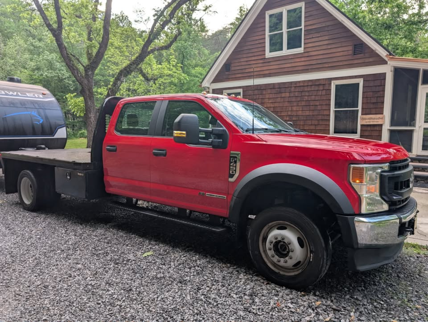 Red 2022 Ford F-450 Super Duty XL flatbed truck, crew cab, dual-rear wheels, with a flatbed extending to the rear and a utility cabinet on the side.