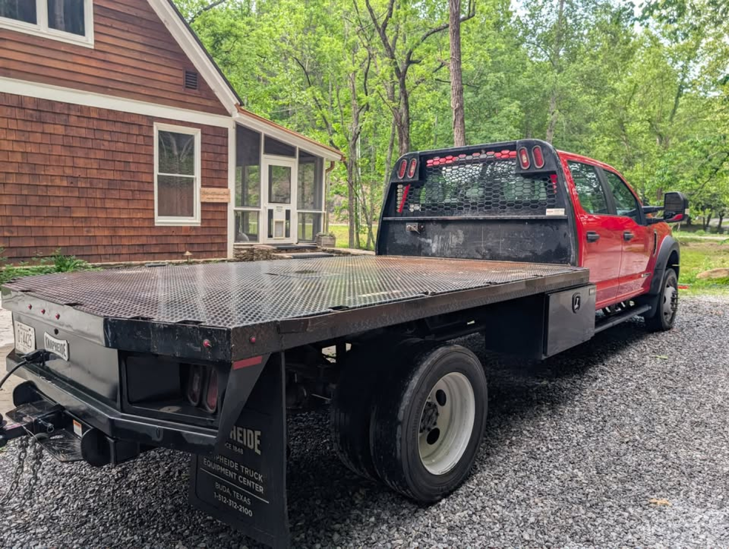 Flatbed tow truck: 2022 Ford F-450 Super Duty XL in a red cab on a black flatbed, dual rear wheels, bumper hitch, utility accents visible.