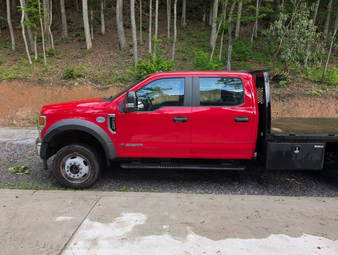 Ford F-450 Super Duty XL crew cab flatbed truck side view showing red cab, black flatbed, dual rear wheel setup and side mirrors.
