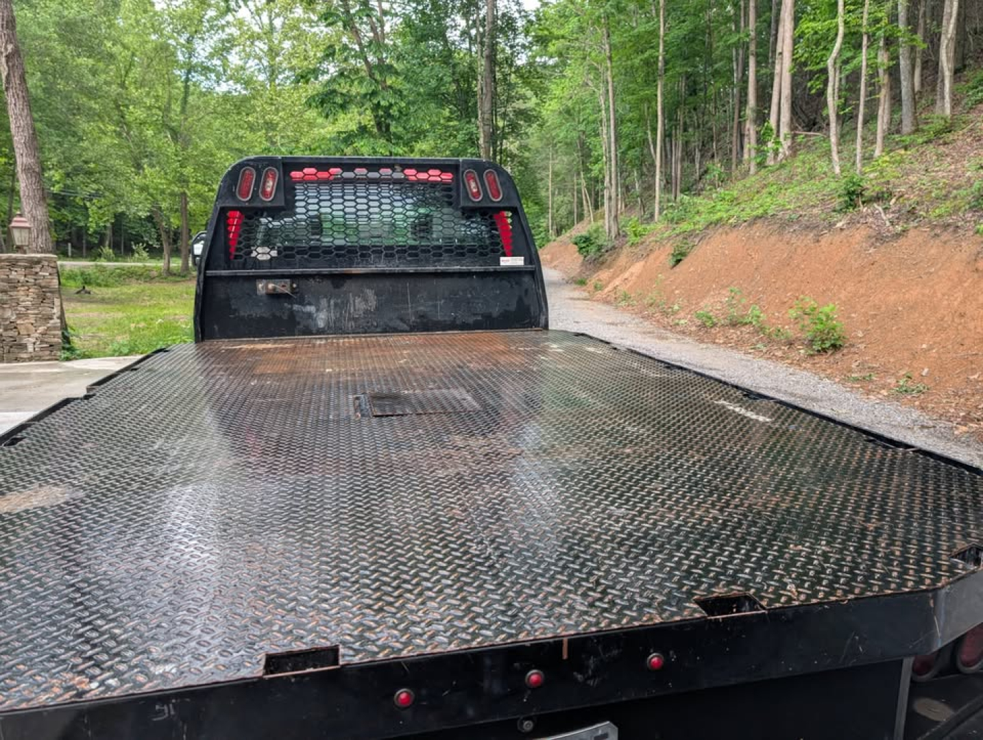 Flatbed of a 2022 Ford F-450 Super Duty XL with a diamond plate steel bed and rear cab support grille.