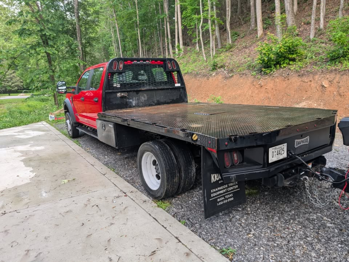 Red Ford F-450 Super Duty XL tow vehicle with a flatbed trailer attached, viewed from the rear left side; trucks category, used condition.
