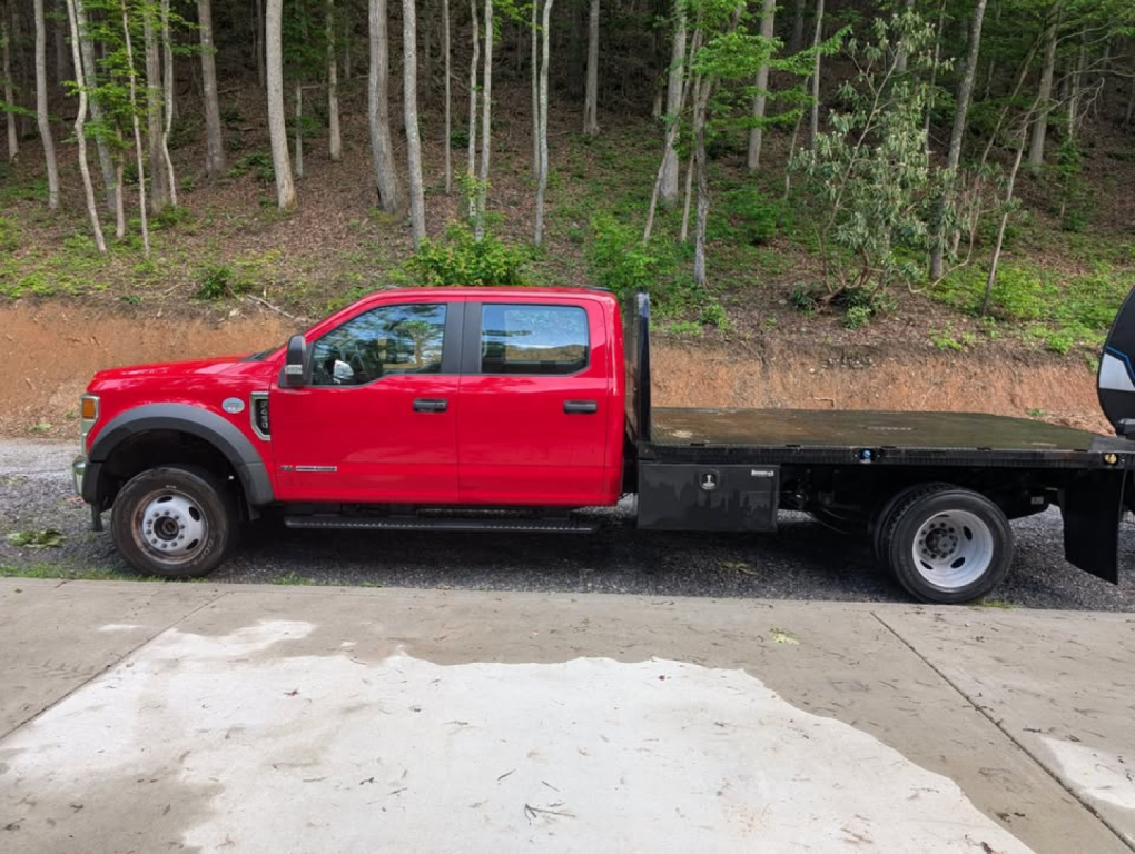 2022 Ford F-450 Super Duty XL flatbed truck side view showing red cab and black flatbed.