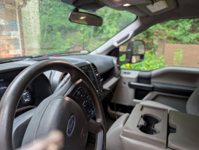 Ford F-450 cab interior showing steering wheel with Ford logo and center console with cup holders.