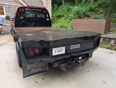 Flatbed tow truck on rear view showing heavy-duty steel platform, hitch and tow bar, taillights, license plate, and Knapheide markings.