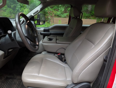 Interior of a 2022 Ford F-450 Super Duty XL with beige/gray seats, front bucket seats, steering wheel, center console, and black floor mats.