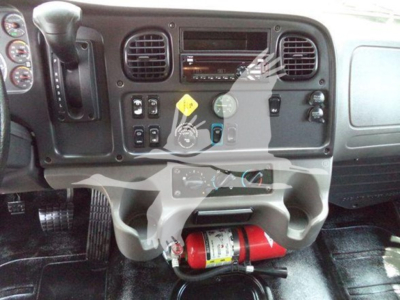 Truck dash of a 2020 Freightliner M2 106 showing steering column, gauges, vents, switches, and a red fire extinguisher mounted beneath the center console.