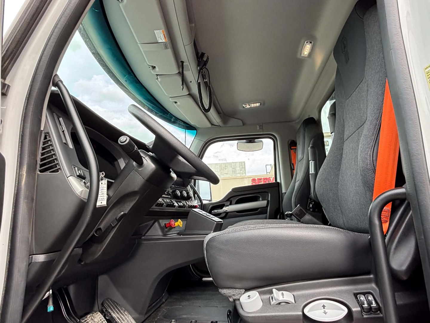 Kenworth T880 cab interior showing steering wheel, dashboard, driver seat, and overhead controls.