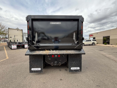 Rear view of a 2025 Kenworth T880 dump truck showing the dump bed with chain latches and dual mud flaps labeled 'ROADFORCE' and hydraulic hitch area.