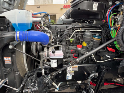 Kenworth T880 engine bay showing blue coolant reservoir and multiple hoses, wiring, and components