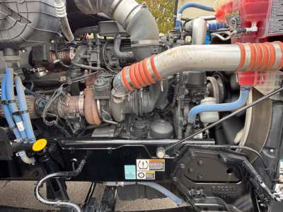 Kenworth T880 engine bay with intercooler hoses, turbocharger, and coolant lines visible in a dump truck, side view showing engine components.