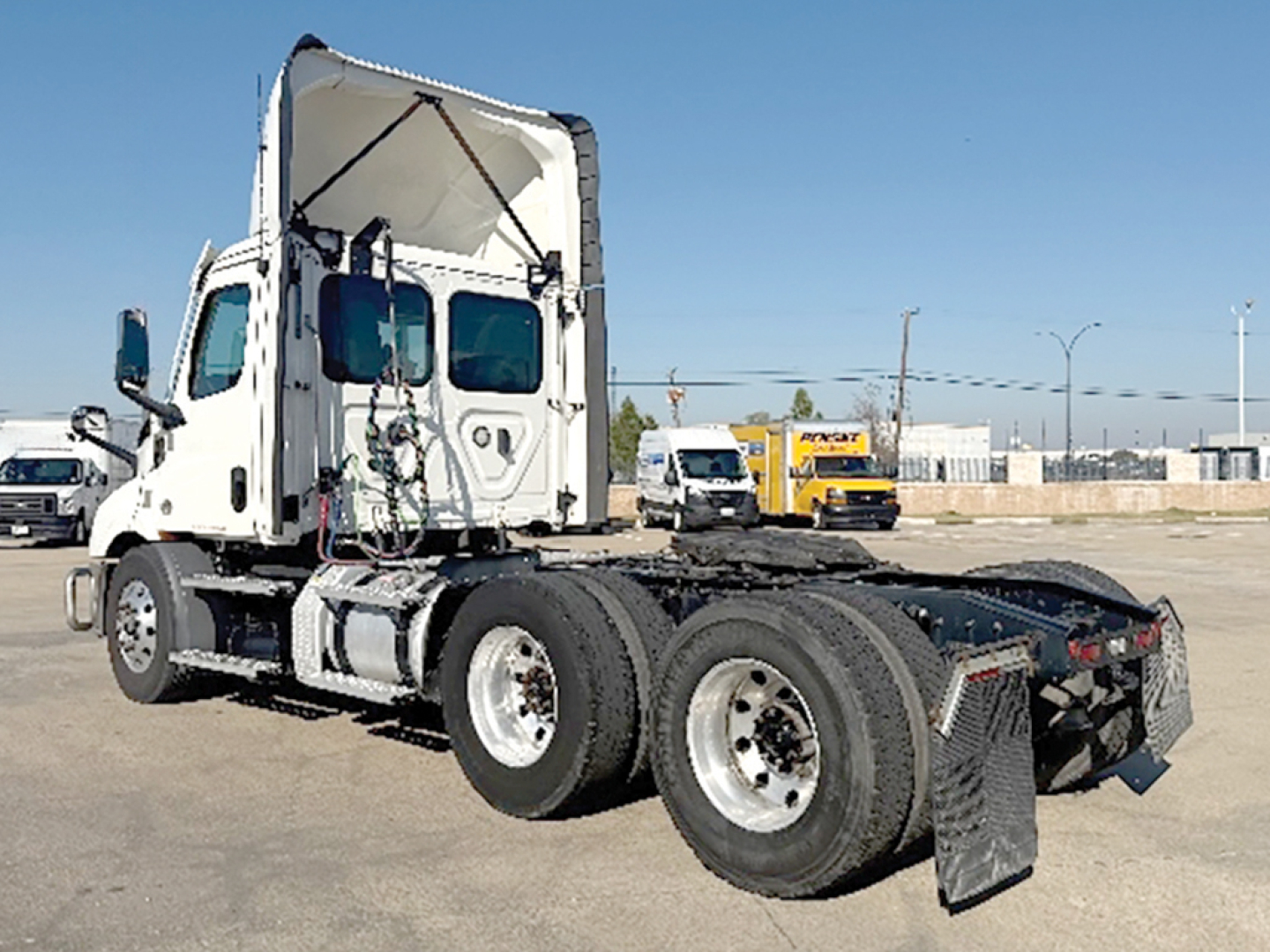 Tractor truck rear three-quarter view showing Freightliner Cascadia 116 chassis with dual rear axles and open sleeper cab.