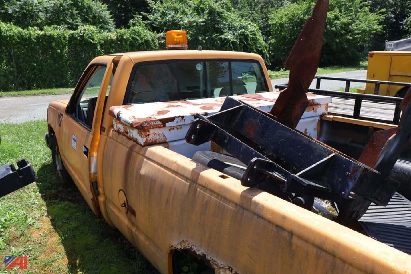 Chevrolet 1993 C/K 1500 pickup truck with rusted bed and equipment in the truck bed, orange warning beacon on cab, side view showing double cab and pickup bed.