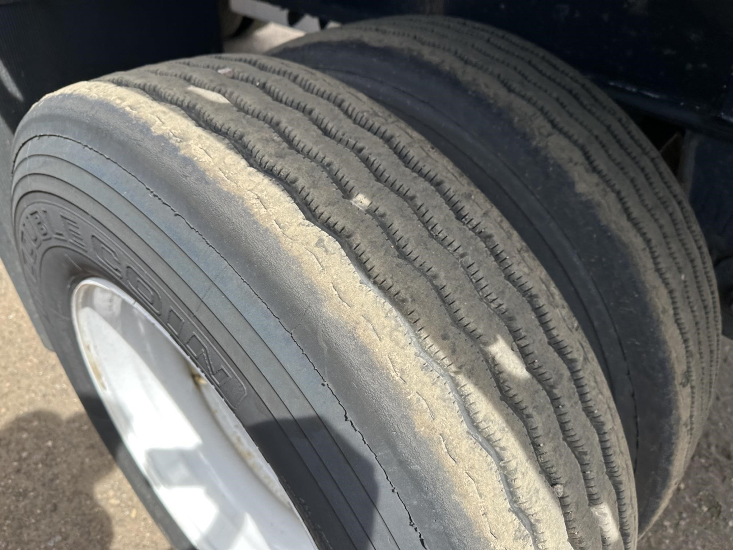 Trailer wheel close-up showing treaded dual tires with sand-colored wear and white rim, part of a Fontaine Infinity flatbed trailer.