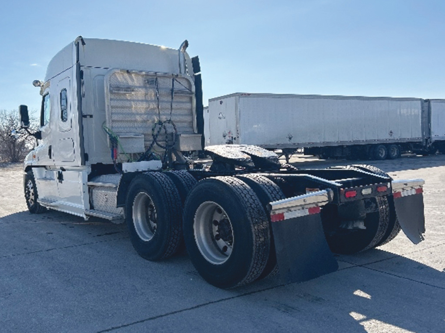 Conventional sleeper Freightliner Cascadia125 tractor rear view showing tandem axle, mud flaps, and fifth-wheel plate.