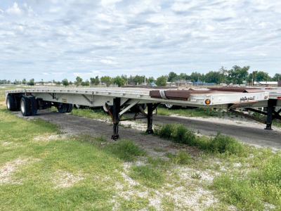 Reitnouer MaxMiser flatbed trailer showing long low deck with tandem axles and landing gear extended.