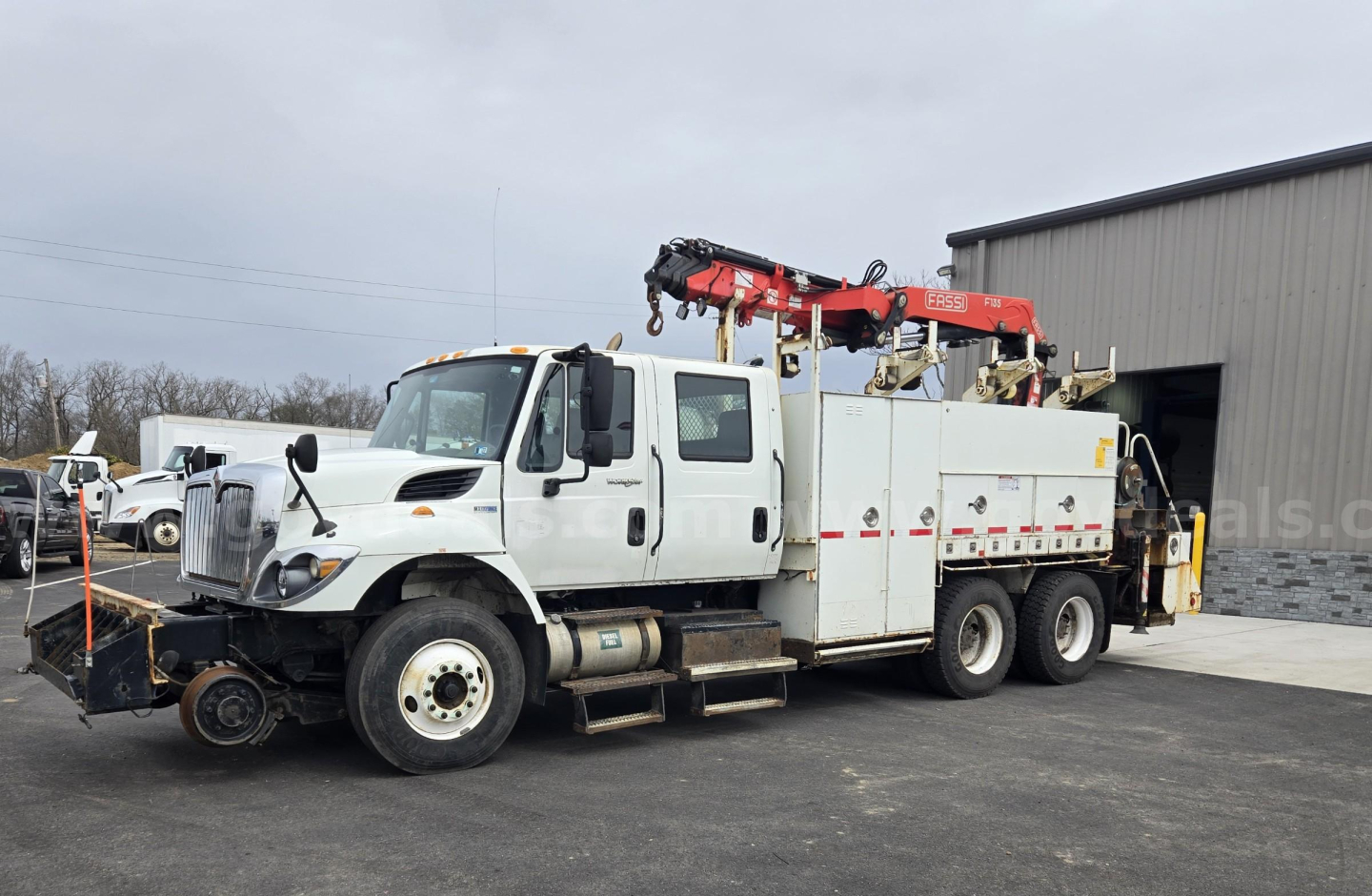 2015 International WorkStar tow truck with mounted crane and utility compartments in a yard.