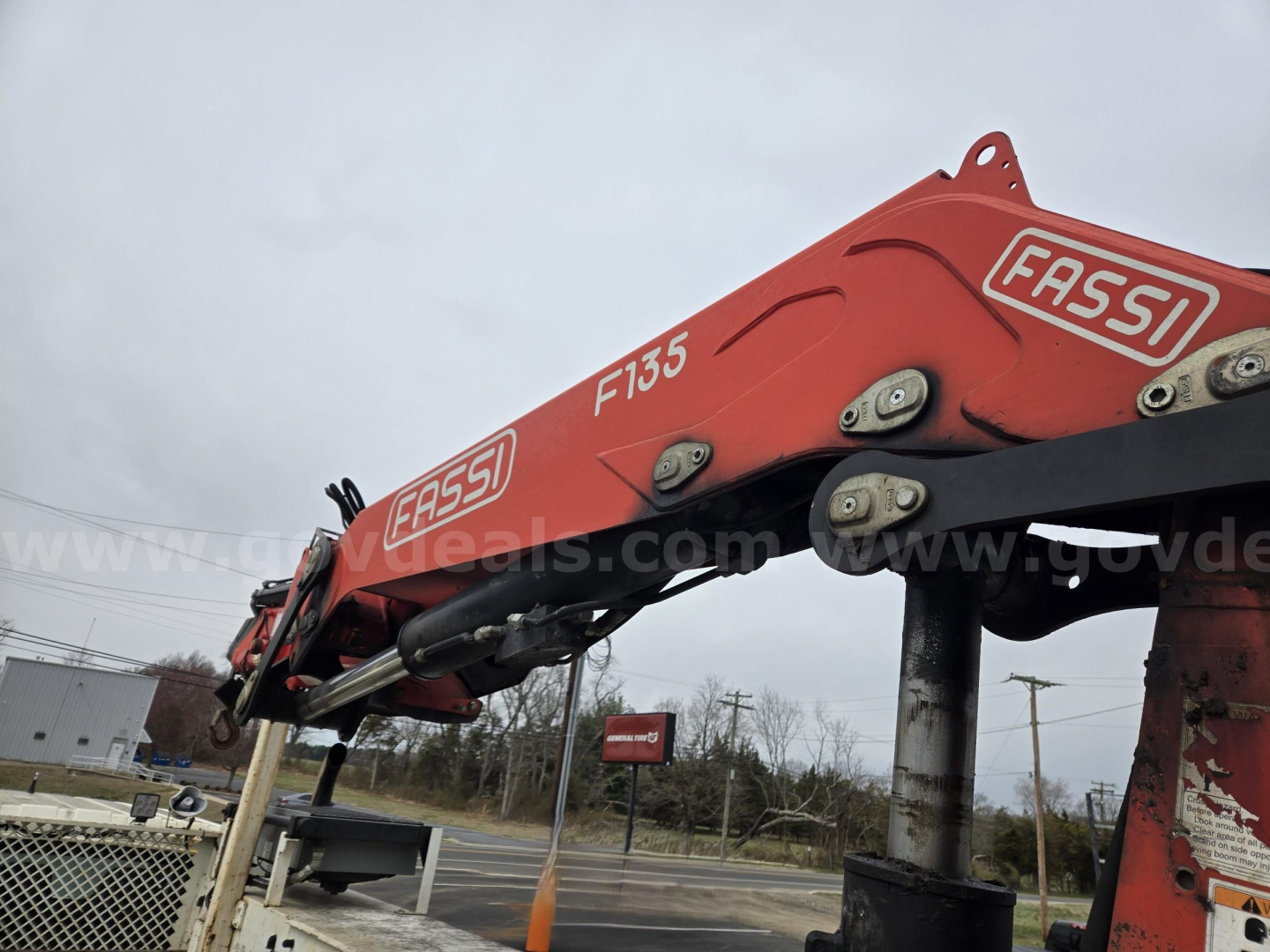 Equipment arm of a red Fassi crane mounted on a truck chassis showing hydraulic boom with Fassi branding and model F135 on the arm.