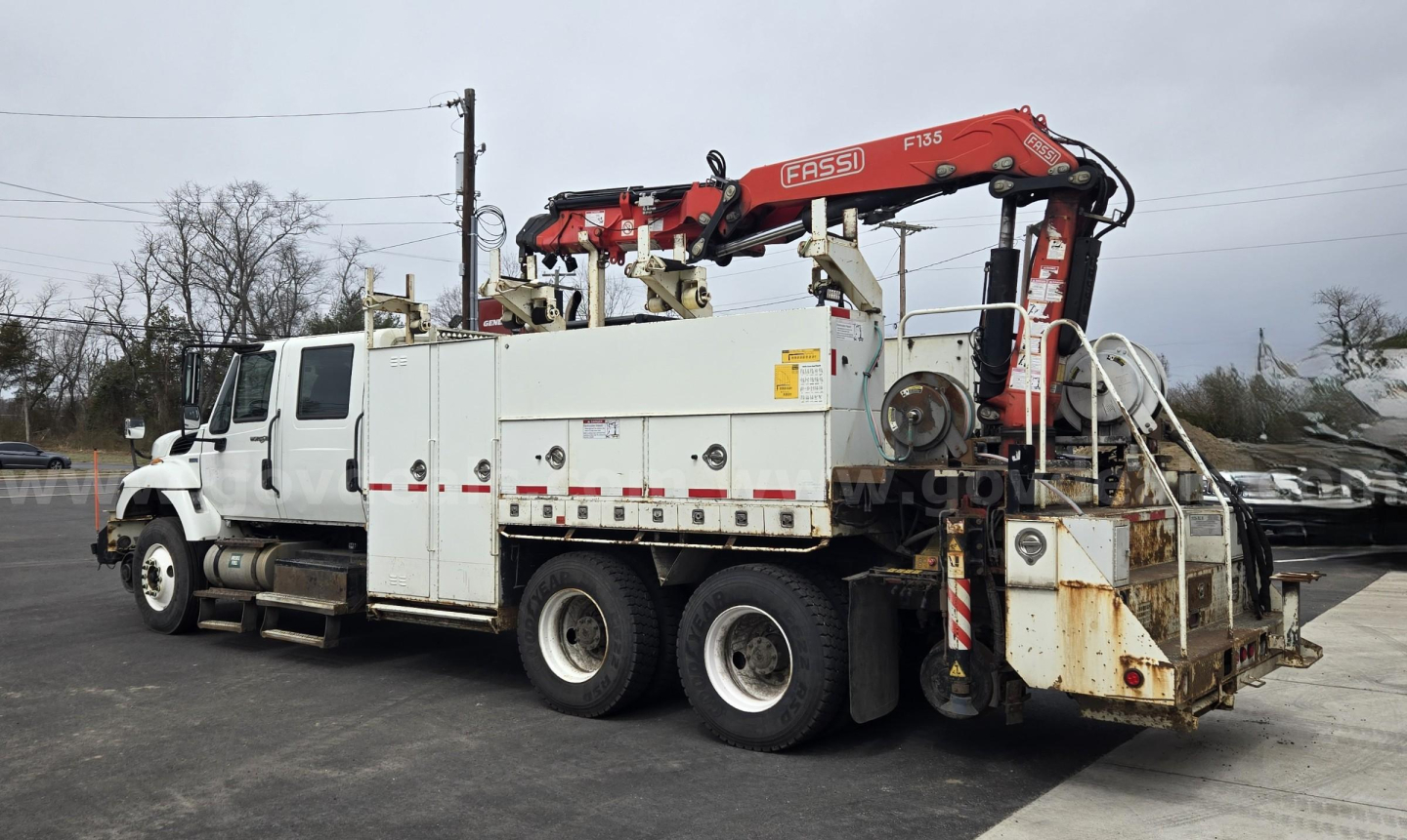 International WorkStar 2015 utility truck with-mounted hydraulic crane and service compartments, side view showing white body and red knuckle crane.