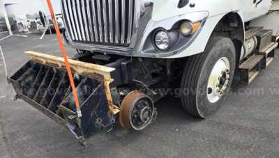 Truck front left side with snowplow attachment; International WorkStar with front dual tires; large chrome grille; wheel and steps visible.