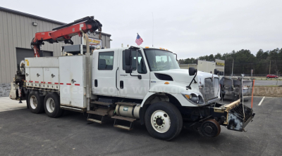 International WorkStar utility truck with crane on a lot, front bumper equipment, white cab, and storage compartments along the side.