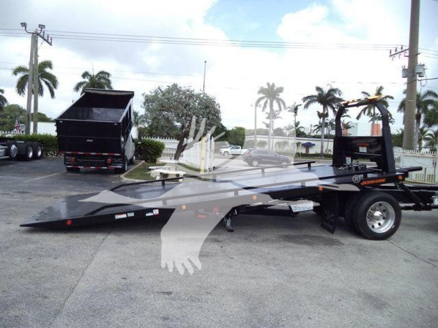 2019 International 4300 rollback tow truck with flat-bed and trailer, visible wheel, ramps, and loading equipment. No legible labels or fluid specs clearly readable in image.