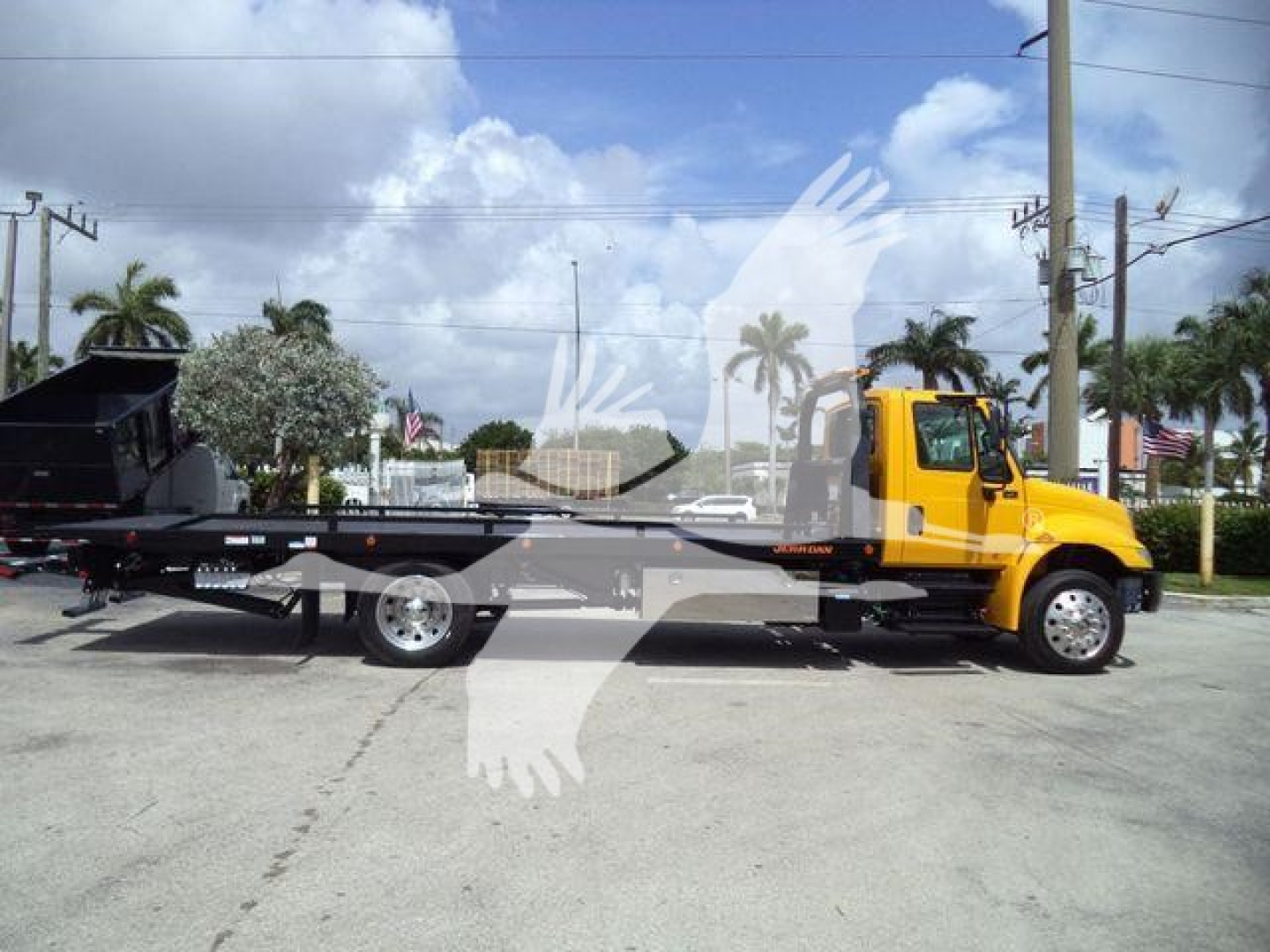 2019 International 4300 rollback truck with yellow cab and flatbed, side profile visible.