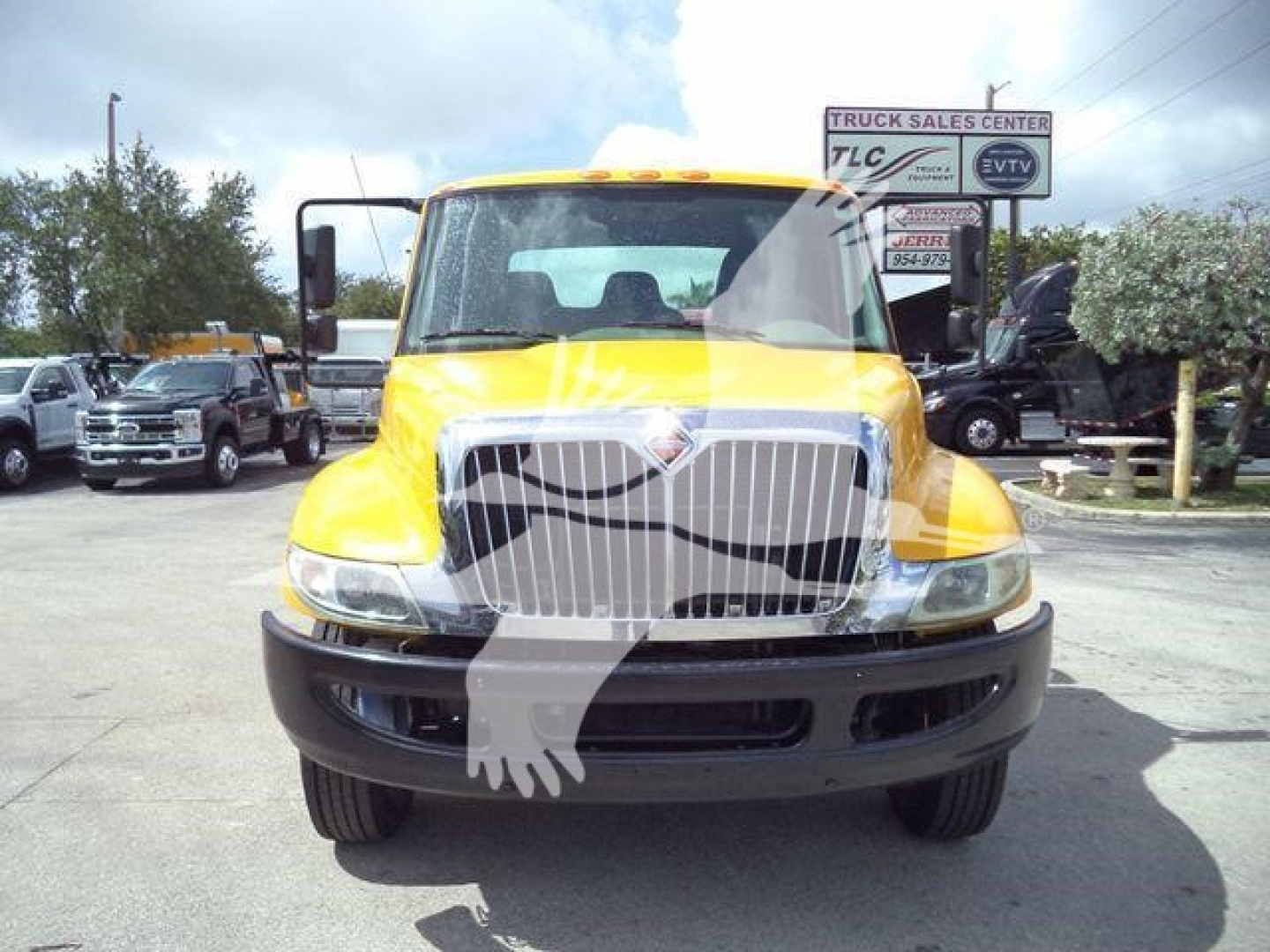Front view of a yellow 2019 International 4300 rollback truck with a large chrome grille and logo, stock number T12255FM visible in background.