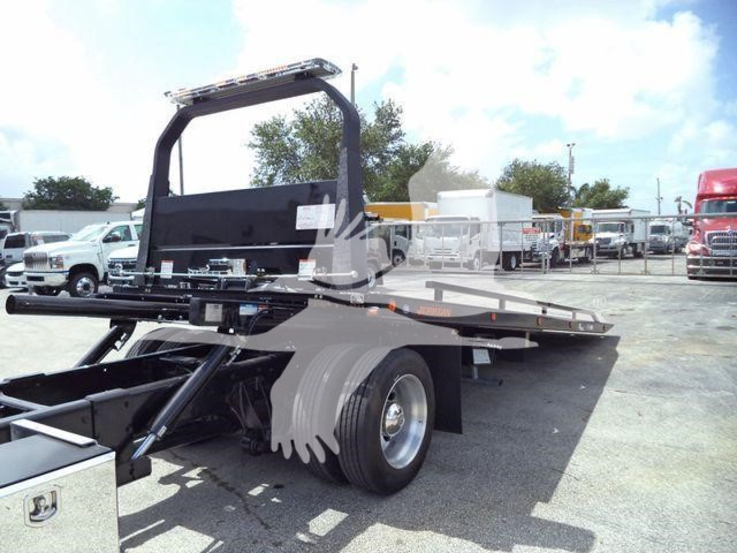 2019 International 4300 rollback truck shown from rear-left side with flatbed and hydraulic system