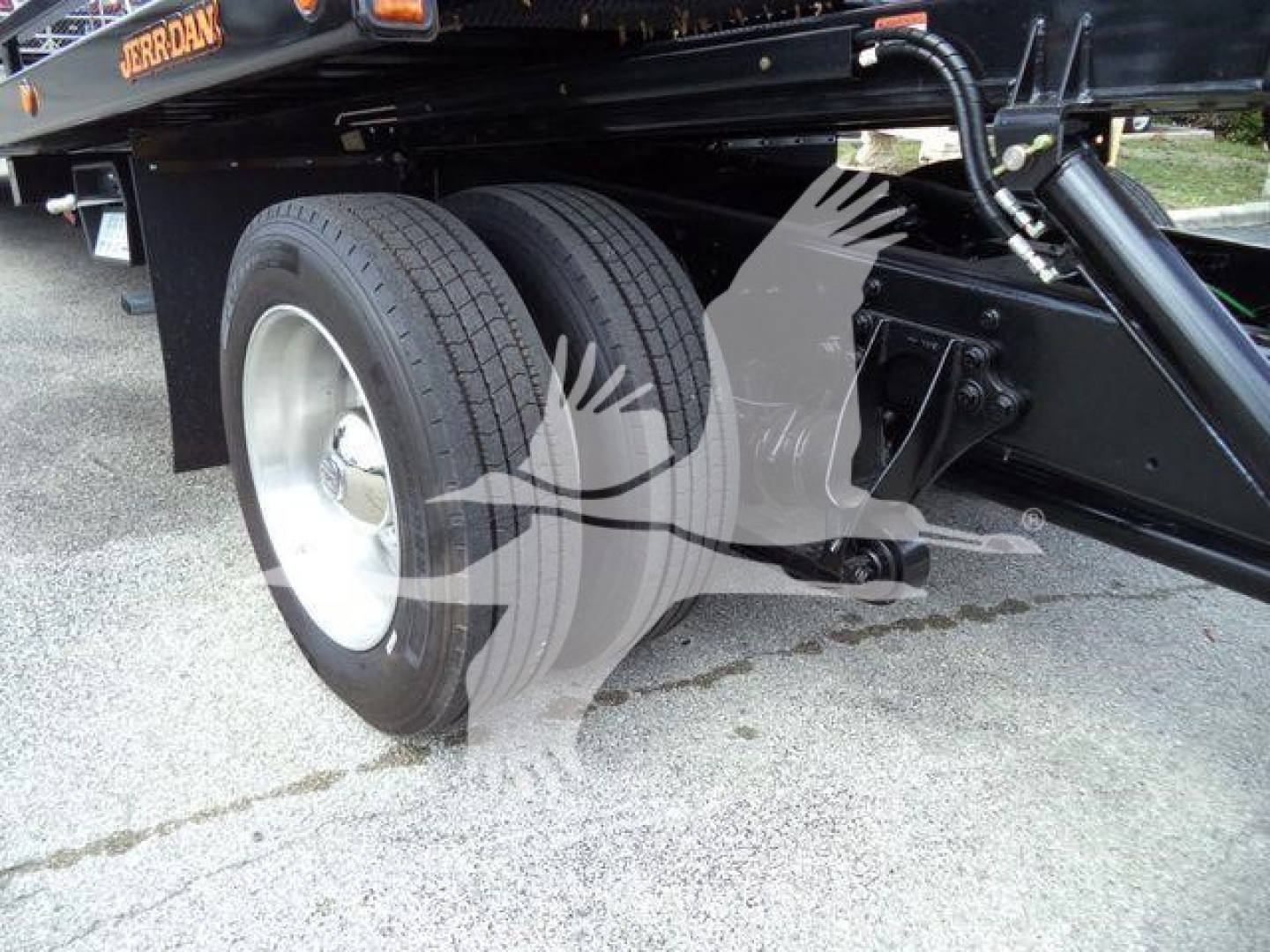 Dual rear wheels on a rollback tow truck chassis with black frame and hydraulic components visible.