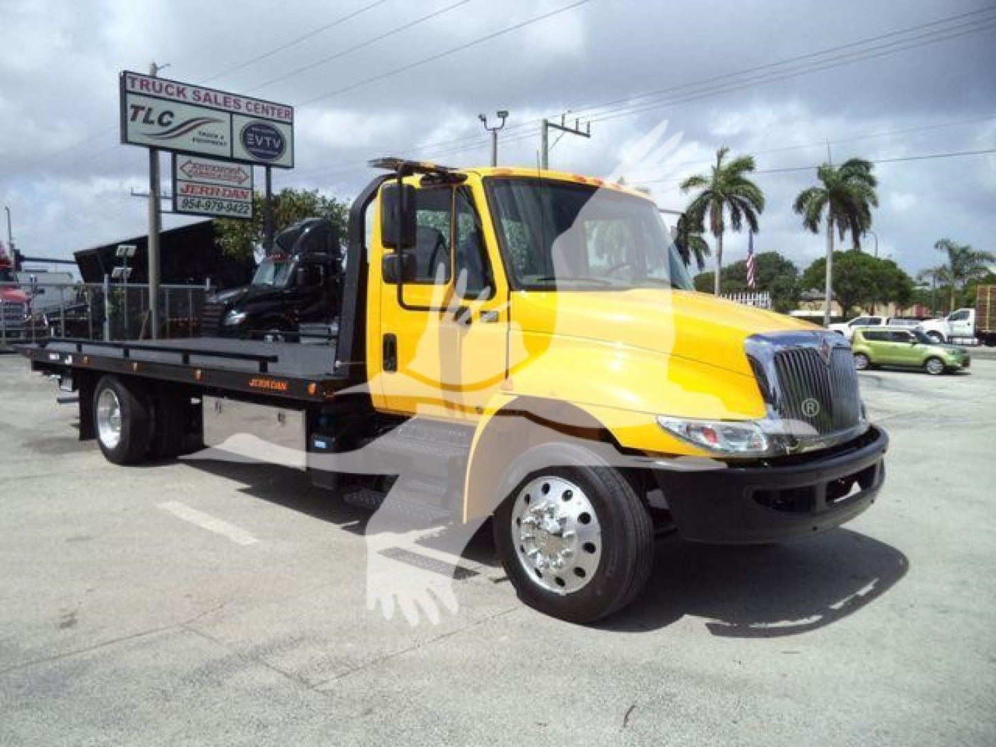 Yellow 2019 International 4300 rollback tow truck seen from side angle with flatbed and crane accessories, stock number T12255FM visible in background.