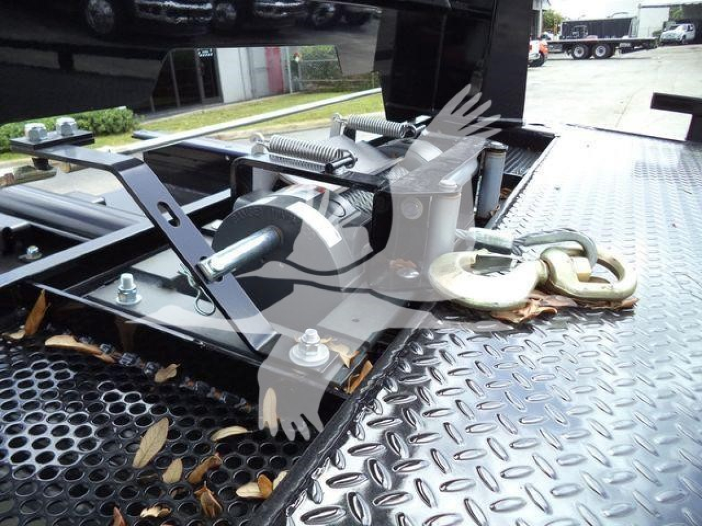 Truck bed with hydraulic winch and hook assembly, mounting hardware, and diamond plate surface.