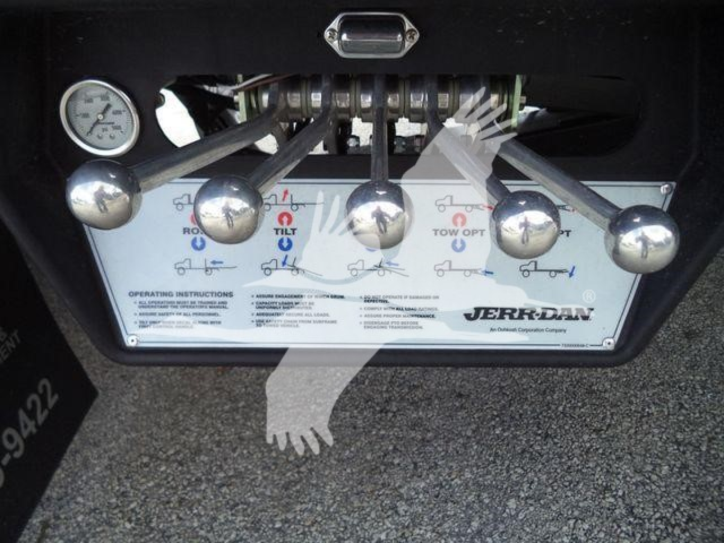 Control levers and operator label on rollover tow truck dashboard showing JBRO-RAM control panel text and diagrams.