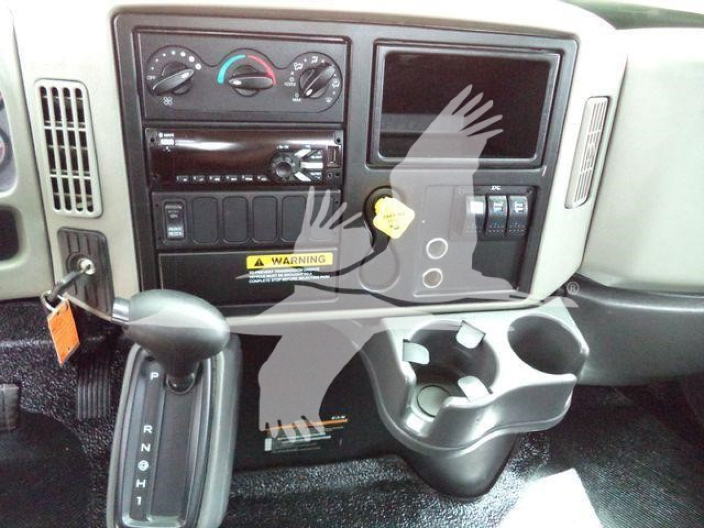 Dashboard and center console of a 2019 International 4300 truck showing instrument cluster, HVAC controls, radio, cup holders, and ignition area.
