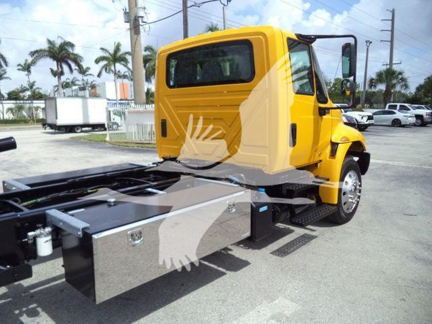 2019 International 4300 rollback truck cab and chassis with bright yellow cab, side toolbox, and flatbed frame in view